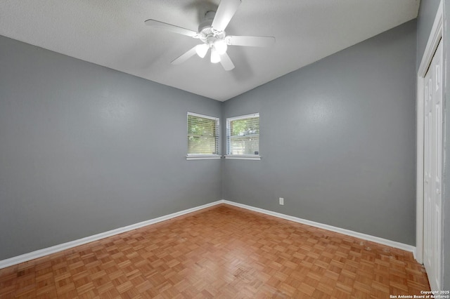 empty room featuring ceiling fan, vaulted ceiling, a textured ceiling, and light parquet floors