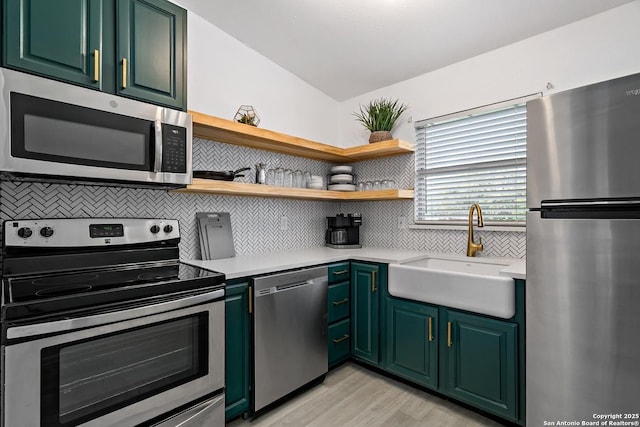 kitchen featuring stainless steel appliances, sink, light wood-type flooring, and decorative backsplash