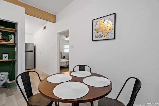 dining area featuring vaulted ceiling with beams, ceiling fan, and light wood-type flooring