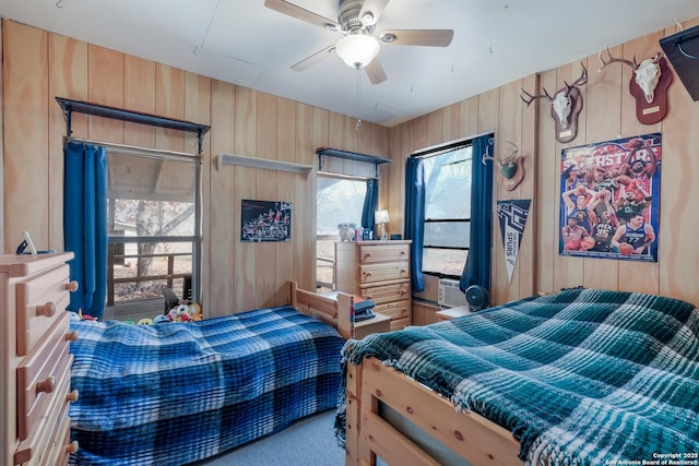 bedroom with cooling unit, ceiling fan, and wood walls