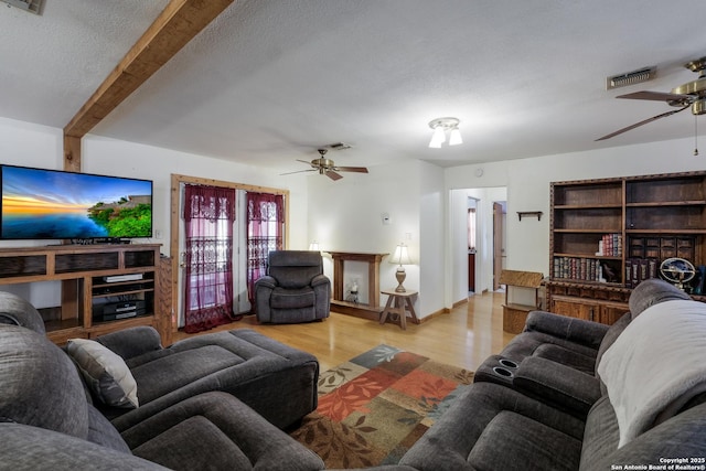 living room with ceiling fan, a textured ceiling, beam ceiling, and light hardwood / wood-style flooring