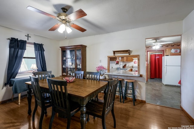 dining space with dark hardwood / wood-style floors, sink, and ceiling fan