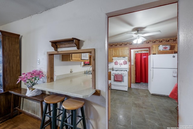 kitchen featuring a breakfast bar, sink, ceiling fan, kitchen peninsula, and white appliances