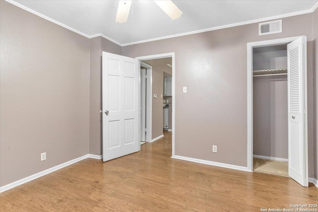 unfurnished bedroom with ceiling fan, ornamental molding, a closet, and light wood-type flooring