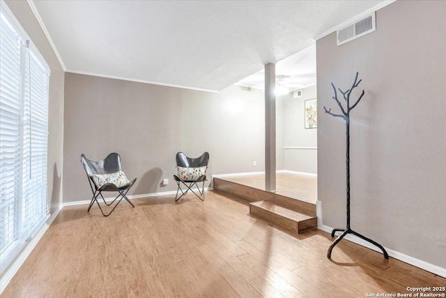 sitting room with ornamental molding, light hardwood / wood-style floors, and a textured ceiling