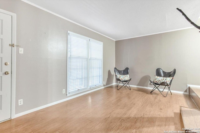 living area with crown molding, a wealth of natural light, and light hardwood / wood-style flooring