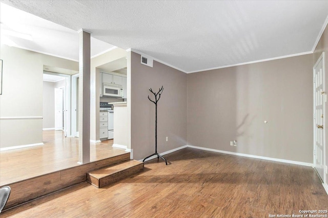 empty room featuring crown molding, wood-type flooring, and a textured ceiling