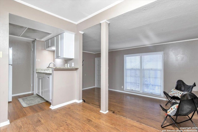 kitchen with decorative columns, white cabinetry, ornamental molding, and light hardwood / wood-style flooring