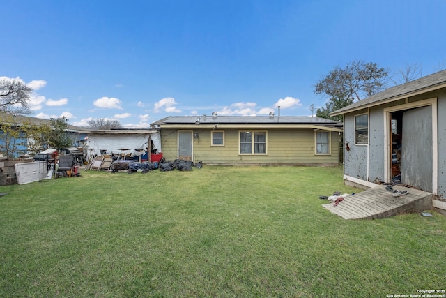 rear view of property with a lawn and solar panels