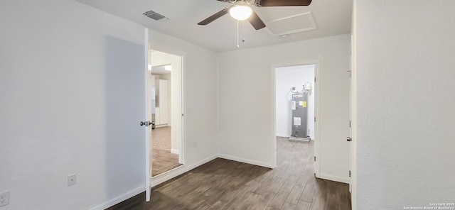 spare room with water heater, ceiling fan, and dark hardwood / wood-style flooring