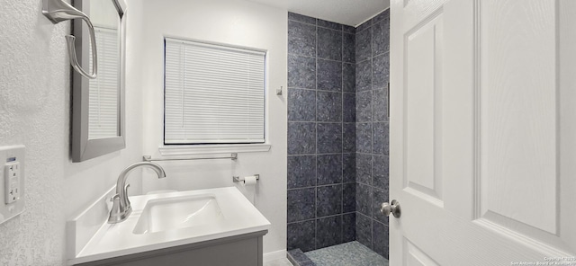 bathroom with a tile shower and vanity