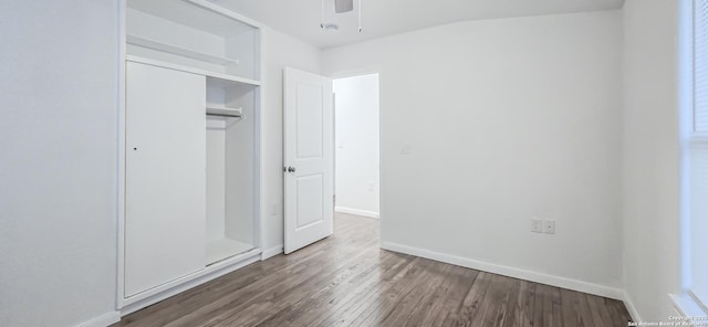 unfurnished bedroom with dark wood-type flooring, ceiling fan, and a closet