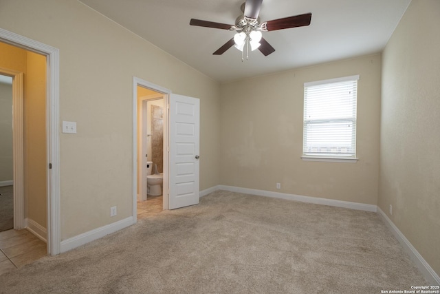 unfurnished bedroom featuring connected bathroom, light colored carpet, and ceiling fan