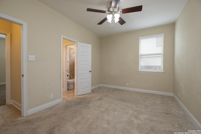 unfurnished bedroom with ceiling fan, ensuite bath, and light colored carpet