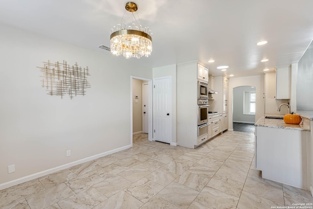 kitchen featuring stainless steel appliances, white cabinetry, and light stone counters