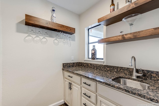 kitchen featuring white cabinetry, sink, and dark stone countertops