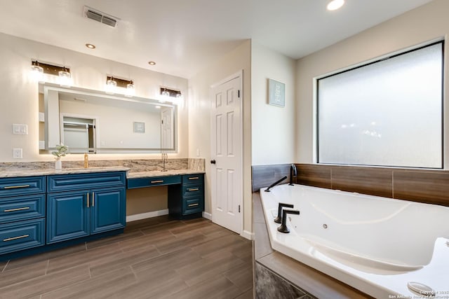 bathroom with vanity and a relaxing tiled tub