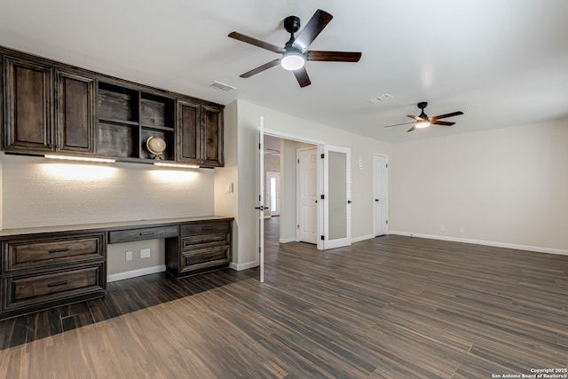 interior space with dark wood-type flooring, built in desk, and ceiling fan