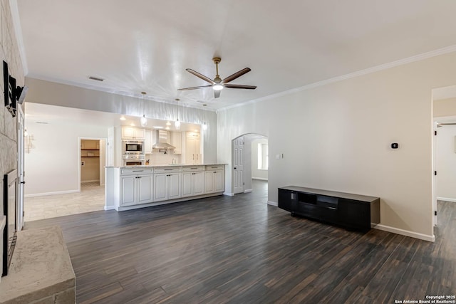 unfurnished living room featuring dark hardwood / wood-style flooring, crown molding, and ceiling fan