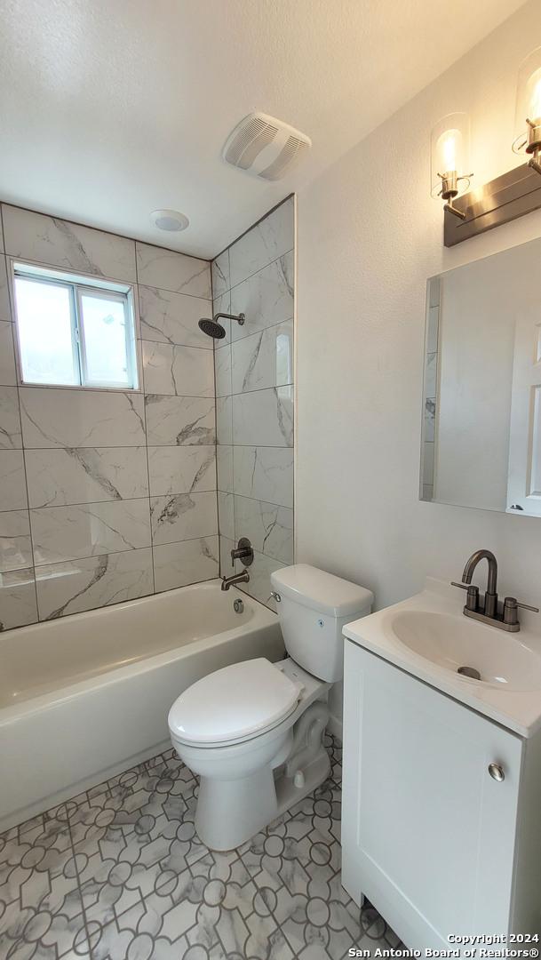 full bathroom with tiled shower / bath combo, vanity, tile patterned flooring, and toilet