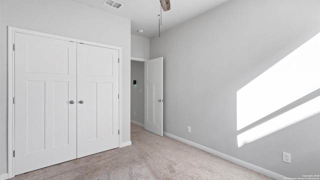 unfurnished bedroom featuring ceiling fan, light colored carpet, and a closet