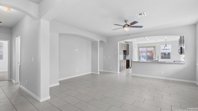 unfurnished living room with light tile patterned flooring and ceiling fan with notable chandelier