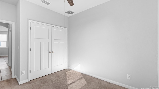 unfurnished bedroom with light colored carpet, ceiling fan, and a closet