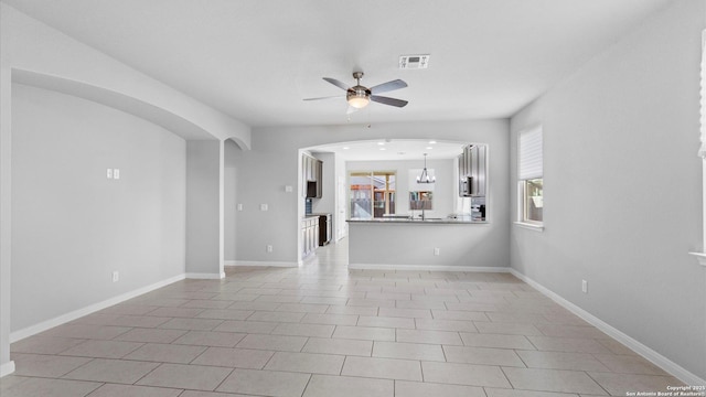 unfurnished living room with light tile patterned flooring and ceiling fan with notable chandelier