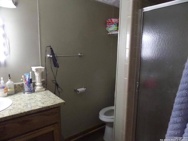 bathroom featuring vanity, toilet, and a shower with door