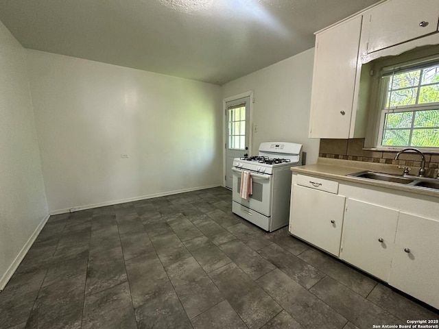 kitchen with backsplash, sink, white gas stove, and white cabinets