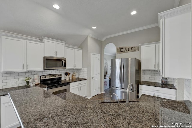 kitchen featuring appliances with stainless steel finishes, dark stone counters, decorative backsplash, and white cabinets