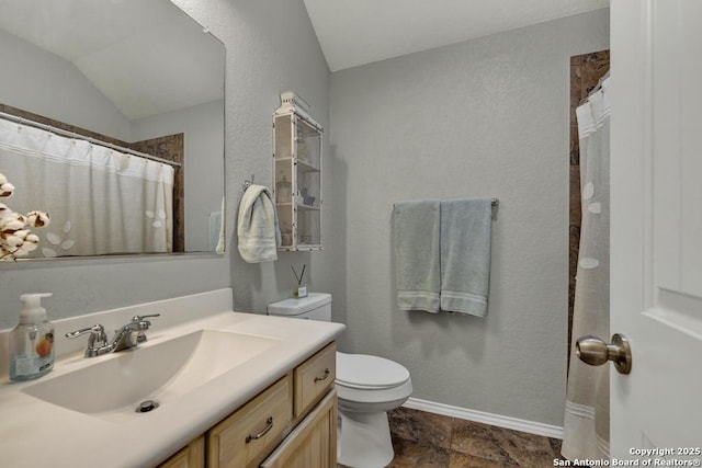 bathroom featuring lofted ceiling, vanity, and toilet