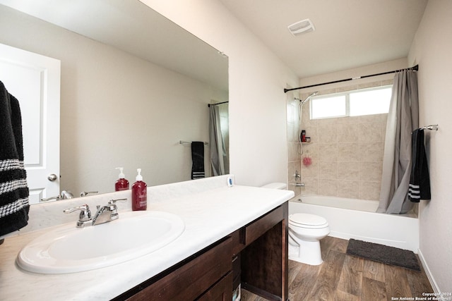 full bathroom featuring hardwood / wood-style flooring, vanity, shower / bath combination with curtain, and toilet