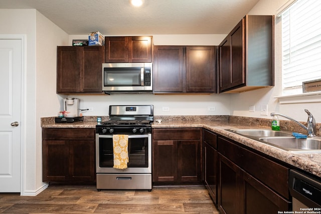 kitchen featuring stainless steel appliances, sink, dark wood-type flooring, and dark brown cabinetry