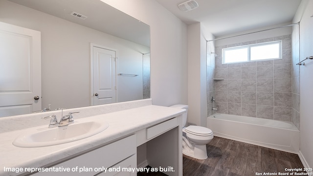 full bathroom with tiled shower / bath, hardwood / wood-style floors, vanity, and toilet