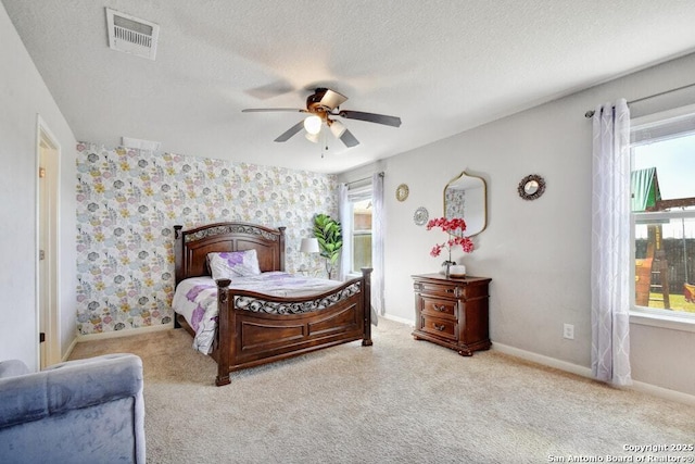 bedroom with ceiling fan, light colored carpet, and a textured ceiling