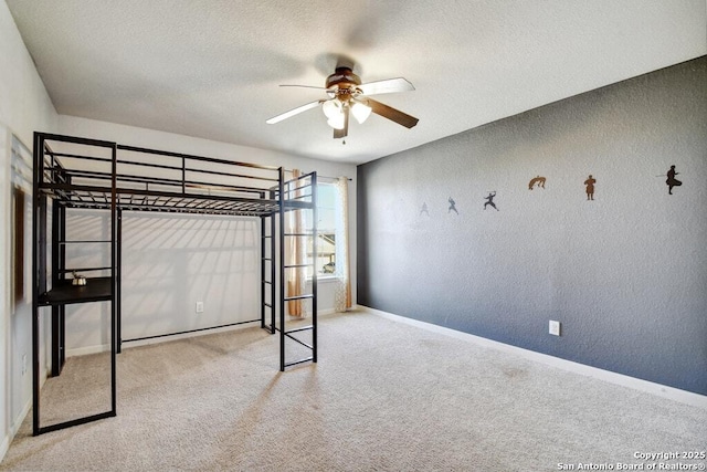 unfurnished bedroom with ceiling fan, light colored carpet, and a textured ceiling