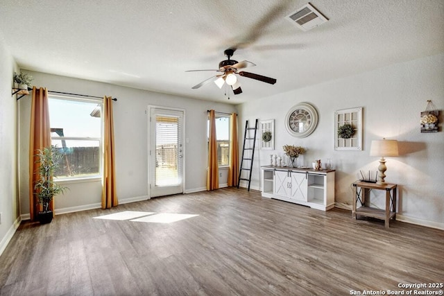 unfurnished living room featuring ceiling fan, hardwood / wood-style flooring, and a textured ceiling