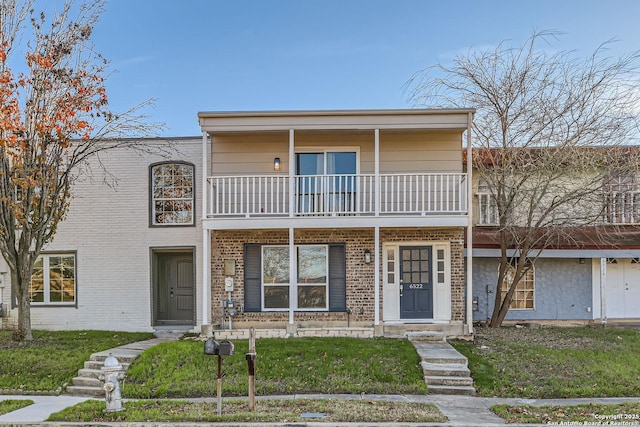 view of front of home with a front yard and a balcony