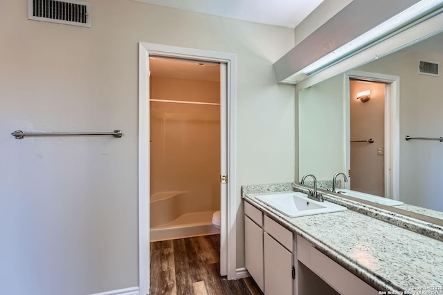 bathroom featuring vanity, wood-type flooring, toilet, and walk in shower