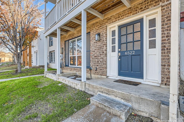 doorway to property featuring a balcony and a lawn