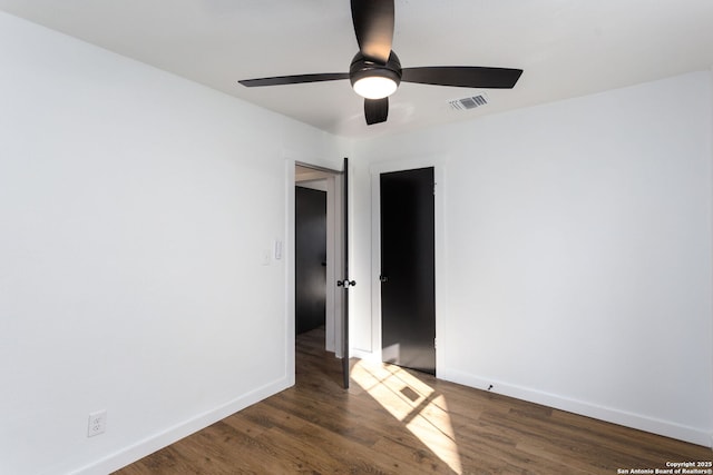 spare room with dark wood-type flooring and ceiling fan