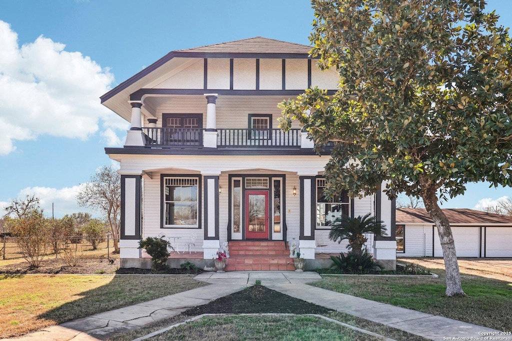 view of front of home with a balcony, covered porch, and a front lawn