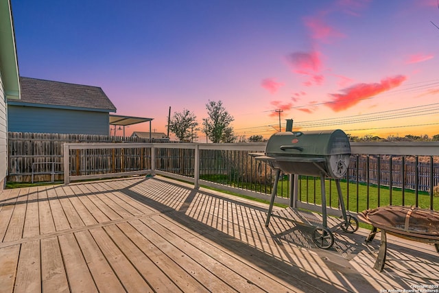 deck at dusk featuring a lawn and an outdoor fire pit