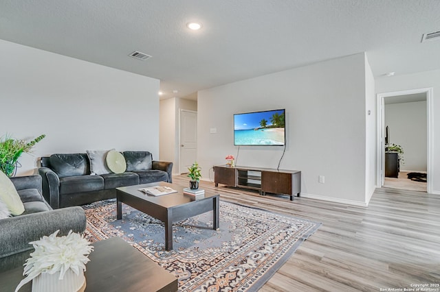 living room featuring light hardwood / wood-style flooring and a textured ceiling