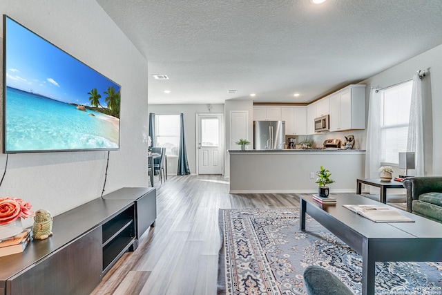 living room featuring a wealth of natural light, light hardwood / wood-style flooring, and a textured ceiling