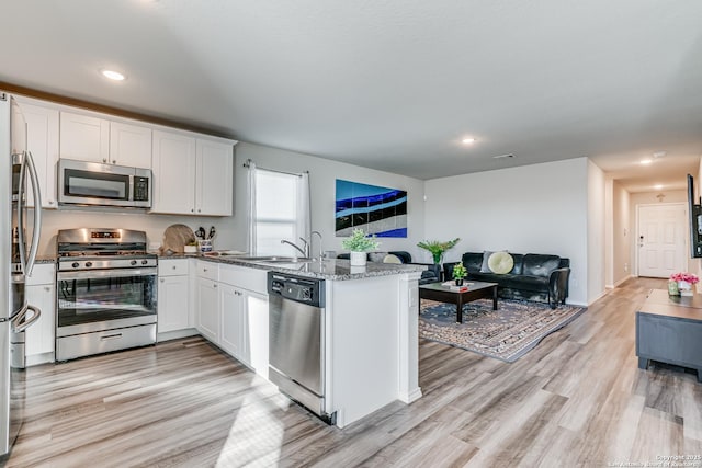 kitchen with sink, stainless steel appliances, light hardwood / wood-style floors, white cabinets, and stone countertops