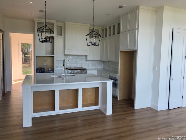 kitchen featuring sink, dark hardwood / wood-style floors, a notable chandelier, a center island with sink, and decorative light fixtures