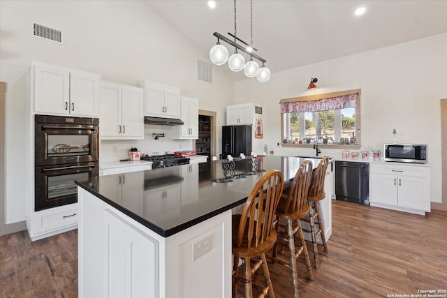 kitchen with dark hardwood / wood-style flooring, black appliances, white cabinets, and a kitchen island