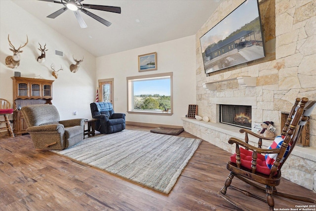 living room featuring hardwood / wood-style flooring, ceiling fan, a fireplace, and vaulted ceiling